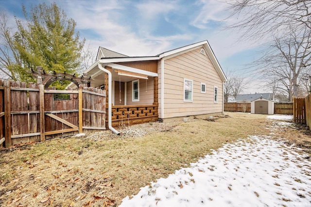 view of snow covered exterior with a storage shed, fence, and an outdoor structure