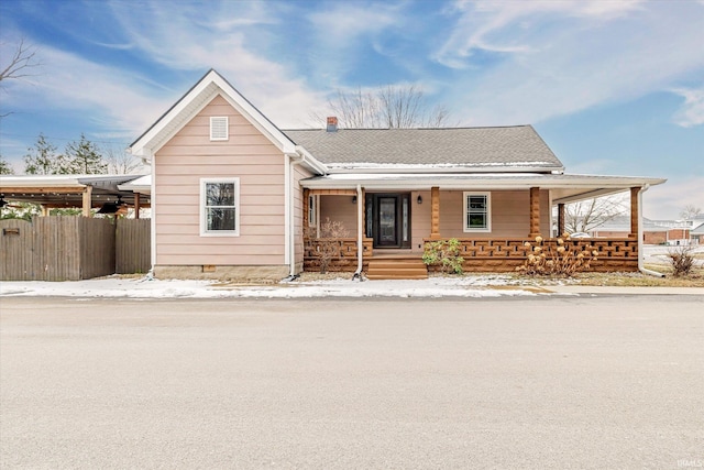 view of front of house with a shingled roof, crawl space, covered porch, and fence