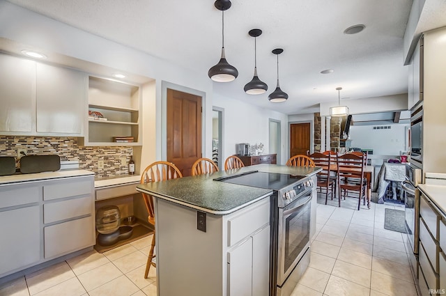 kitchen featuring dark countertops, stainless steel electric range oven, a center island, a kitchen bar, and pendant lighting