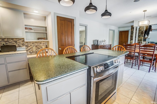 kitchen with electric range, decorative backsplash, decorative light fixtures, a center island, and light tile patterned flooring