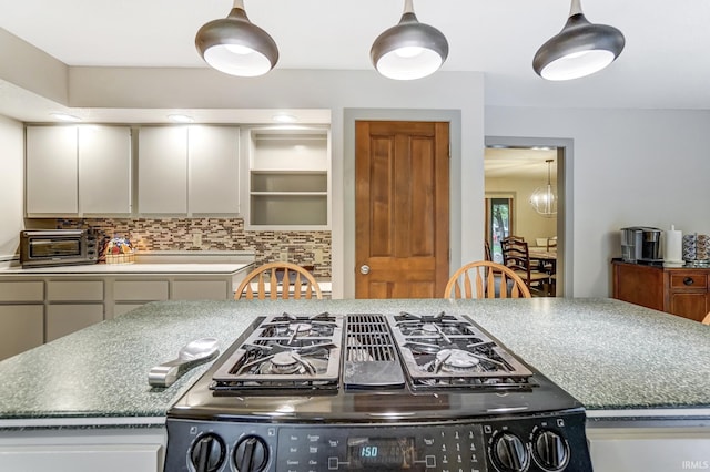 kitchen with tasteful backsplash, gas stove, a toaster, and decorative light fixtures