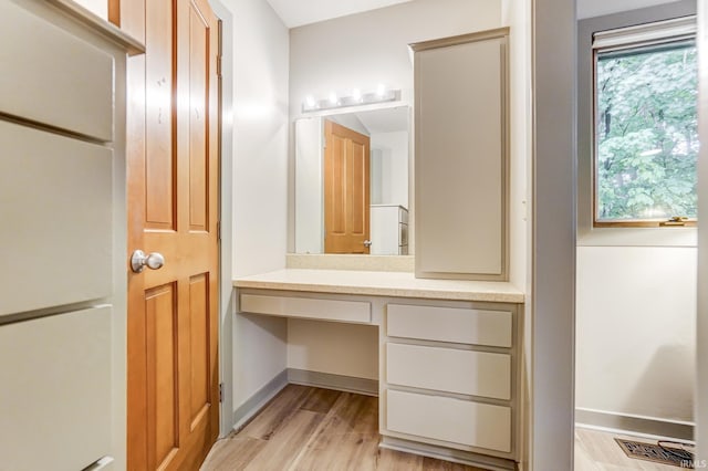 bathroom with baseboards, wood finished floors, vanity, and a healthy amount of sunlight