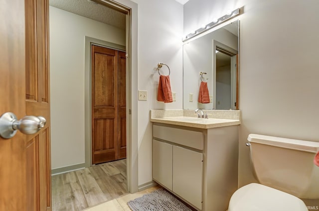 bathroom with vanity, toilet, and a textured ceiling