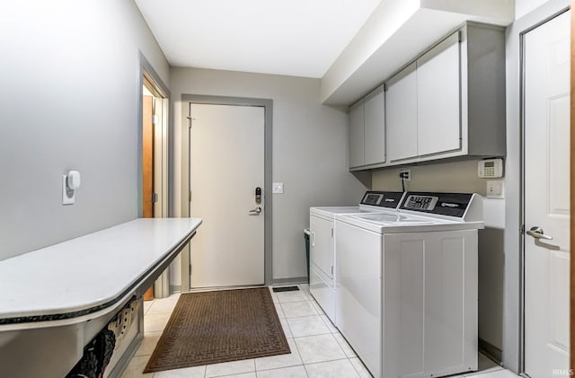 laundry room with light tile patterned floors, washing machine and dryer, and cabinet space