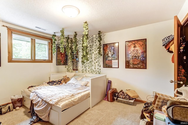 bedroom featuring a textured ceiling, visible vents, and light colored carpet