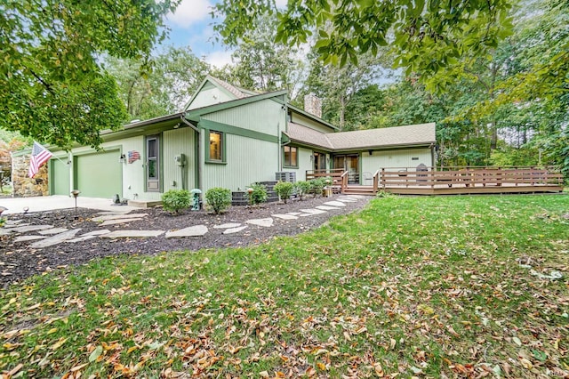 view of front facade with a front lawn, concrete driveway, a chimney, and an attached garage