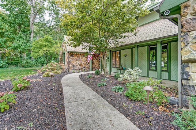 exterior space featuring stone siding, a porch, and roof with shingles