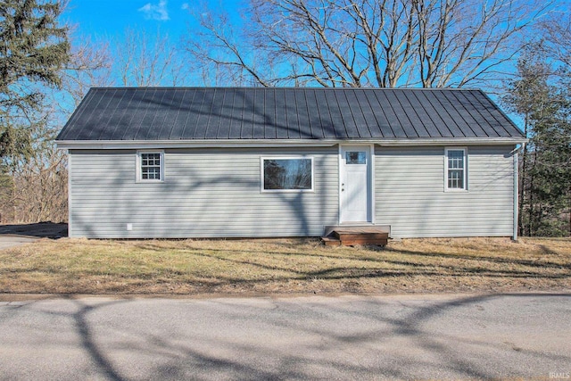 view of front of property with entry steps, metal roof, and a front lawn