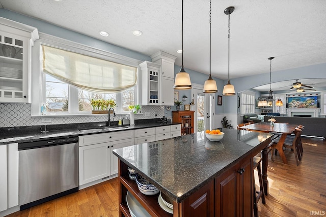 kitchen featuring glass insert cabinets, white cabinetry, dishwasher, and a sink