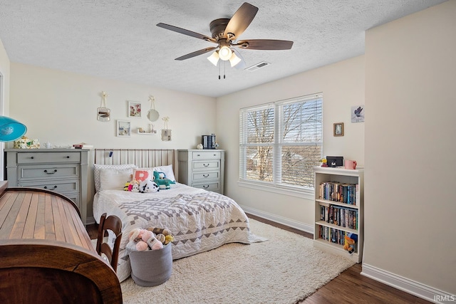 bedroom featuring baseboards, a textured ceiling, visible vents, and dark wood-type flooring