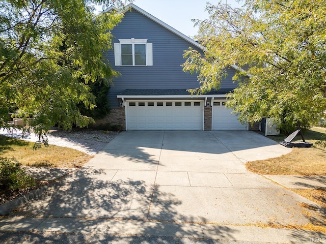 traditional home with a garage, stone siding, and concrete driveway