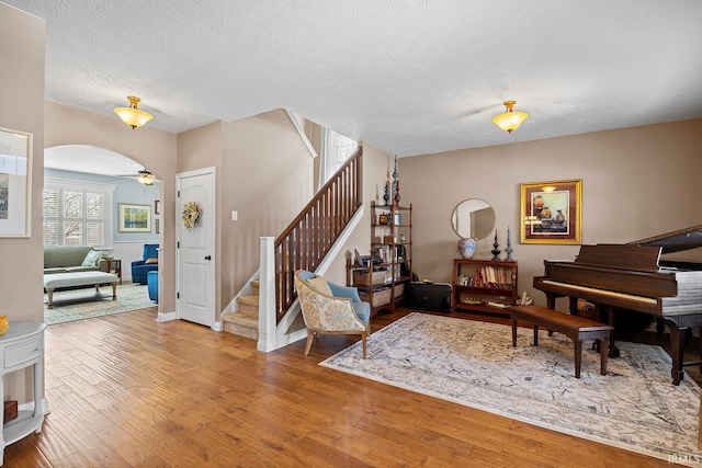 entryway with a textured ceiling, stairs, arched walkways, and hardwood / wood-style floors