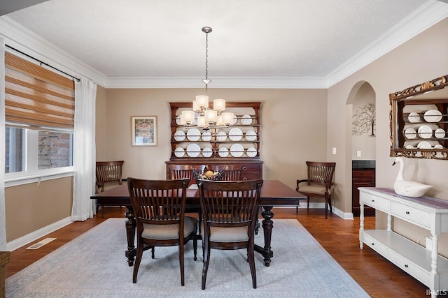 dining area featuring a chandelier, arched walkways, visible vents, ornamental molding, and dark wood-style floors