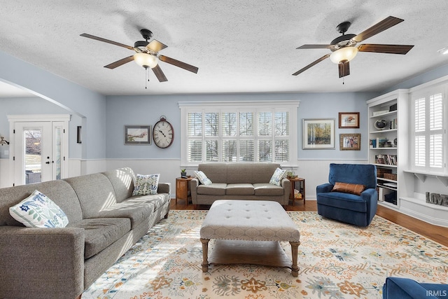 living area with a healthy amount of sunlight, a wainscoted wall, and wood finished floors