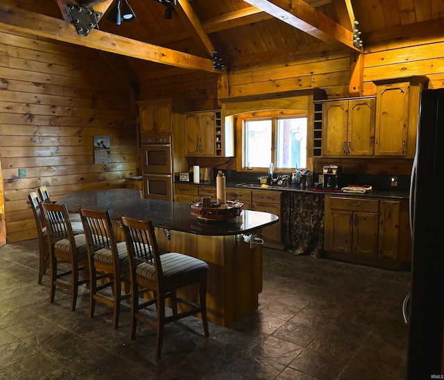 kitchen featuring a breakfast bar, freestanding refrigerator, dark countertops, and open shelves