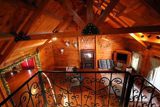 interior space featuring vaulted ceiling with beams, wood walls, wooden ceiling, and a ceiling fan