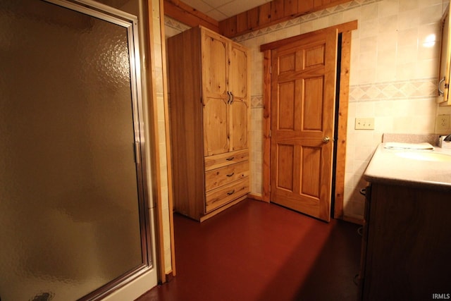 bathroom featuring a stall shower, tile walls, and vanity