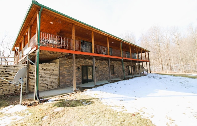 back of property featuring stone siding and a deck