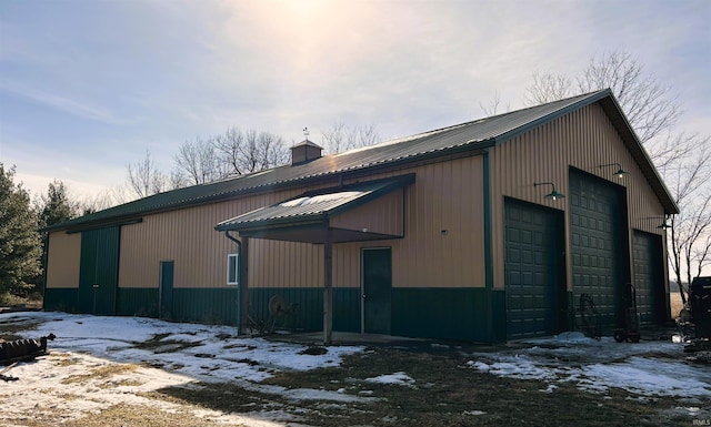 exterior space featuring metal roof, a detached garage, a chimney, and an outdoor structure