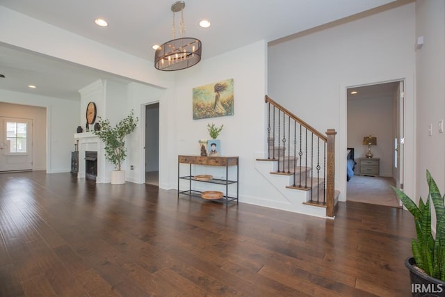 living area with stairs, dark wood-type flooring, a fireplace, and recessed lighting