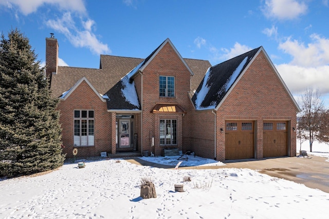 view of front of house with brick siding, driveway, a chimney, and an attached garage