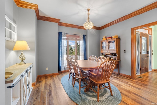 dining space featuring light wood finished floors, baseboards, ornamental molding, and a chandelier