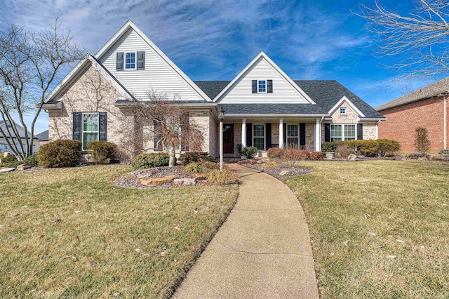 view of front of property with a porch, roof with shingles, and a front yard