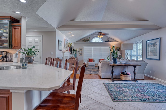 dining area with light tile patterned floors, a ceiling fan, lofted ceiling, ornamental molding, and a textured ceiling