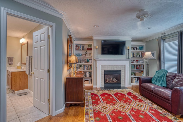 living room featuring built in shelves, crown molding, a fireplace, and a textured ceiling