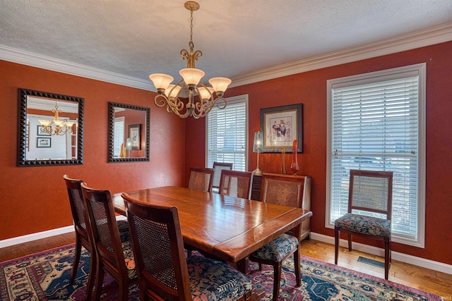 dining room with a textured ceiling, ornamental molding, a notable chandelier, and wood finished floors