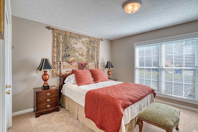 bedroom with light carpet, a textured ceiling, and baseboards