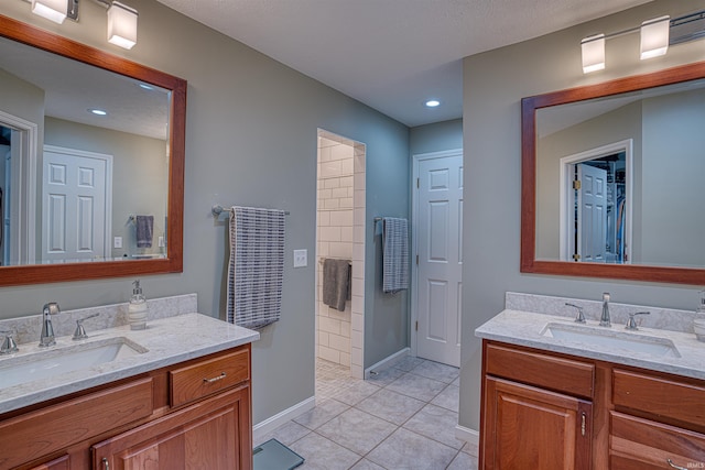 full bathroom featuring baseboards, two vanities, a sink, and tile patterned floors