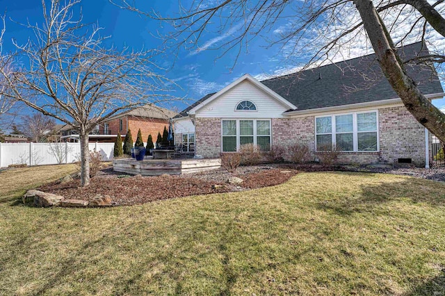 rear view of house with a shingled roof, fence, a lawn, and brick siding