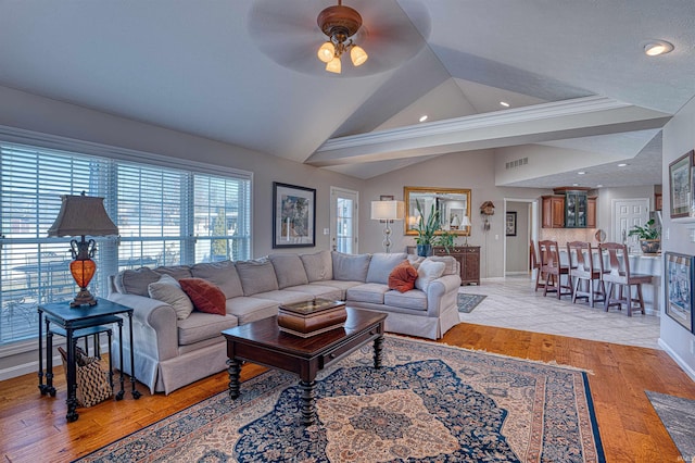 living area with baseboards, visible vents, ceiling fan, vaulted ceiling, and light wood-style floors