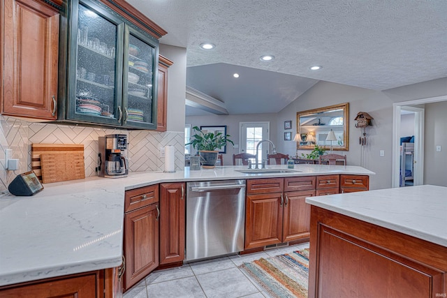 kitchen with light tile patterned floors, tasteful backsplash, dishwasher, glass insert cabinets, and a sink