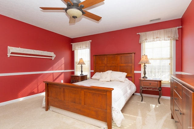 bedroom with light colored carpet, visible vents, and multiple windows