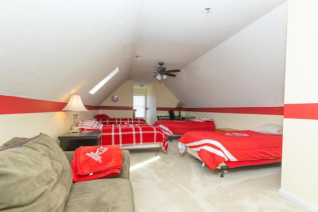 carpeted bedroom featuring a textured ceiling, vaulted ceiling with skylight, ceiling fan, and baseboards