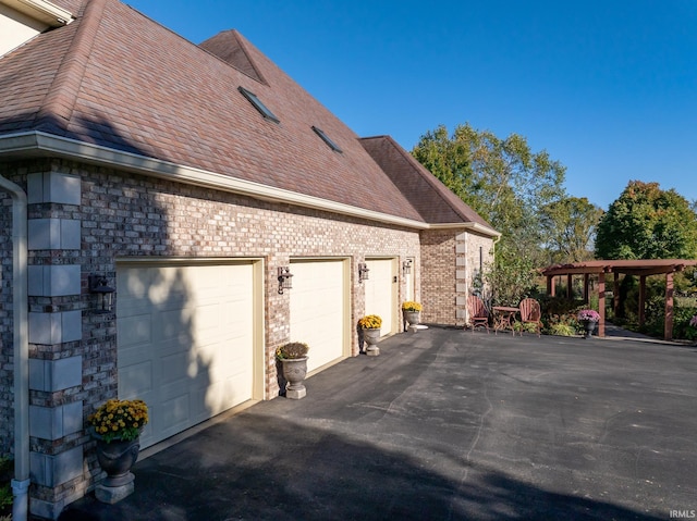 view of side of property featuring a garage, roof with shingles, and brick siding