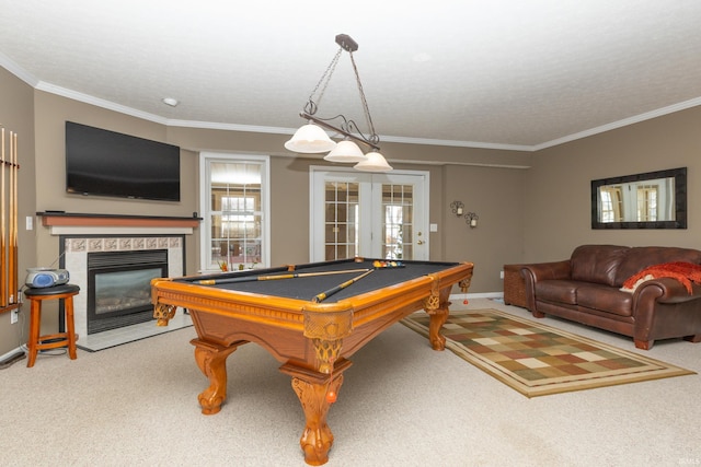 recreation room with french doors, crown molding, light colored carpet, a tiled fireplace, and billiards