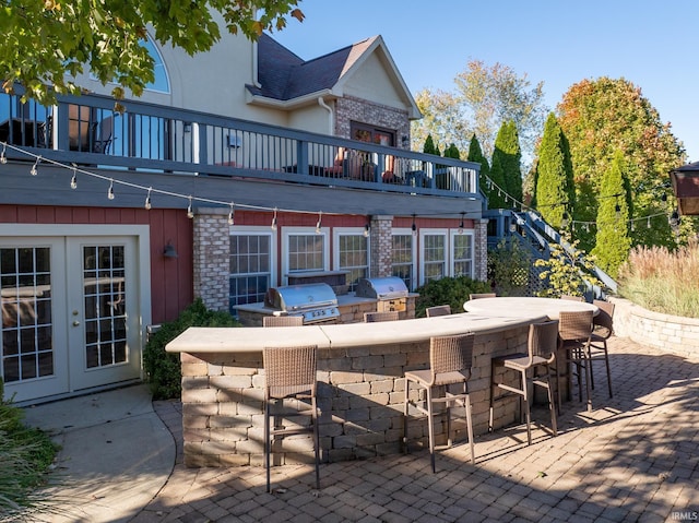 rear view of house featuring an outdoor kitchen, brick siding, french doors, an outdoor bar, and a patio area