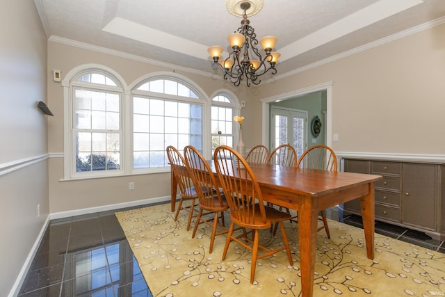 dining area with a chandelier, granite finish floor, baseboards, ornamental molding, and a raised ceiling