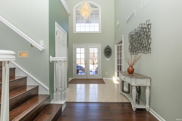 foyer entrance featuring french doors, a notable chandelier, visible vents, stairway, and wood finished floors