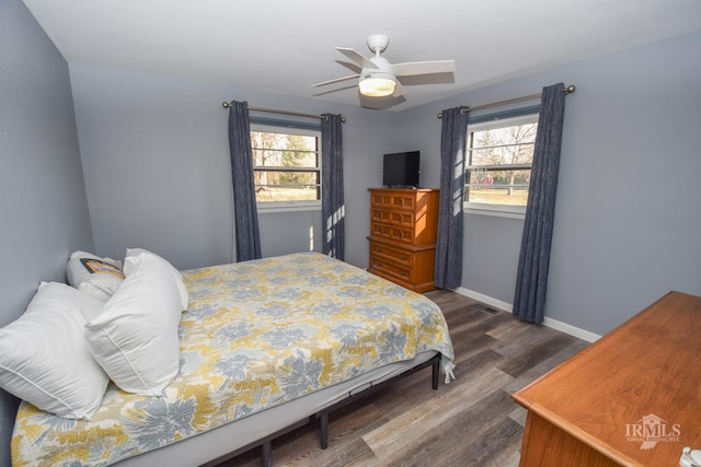 bedroom with multiple windows, baseboards, dark wood finished floors, and a ceiling fan