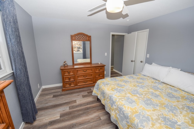 bedroom featuring a ceiling fan, a closet, baseboards, and wood finished floors