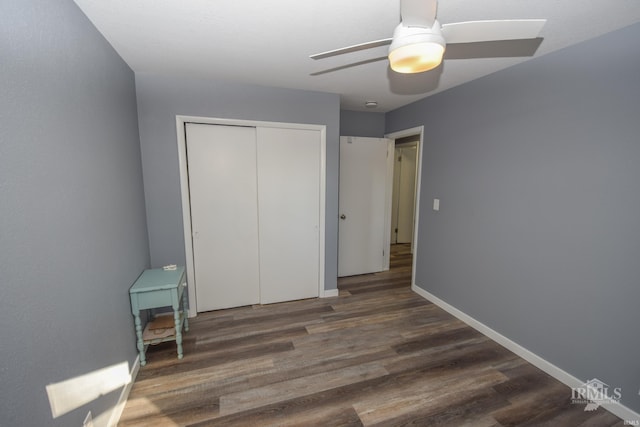 bedroom with a closet, dark wood-style flooring, ceiling fan, and baseboards