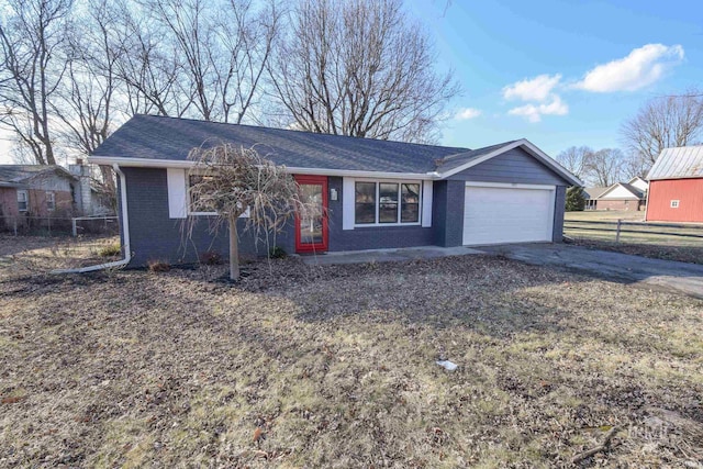 ranch-style house featuring driveway, a garage, fence, and brick siding