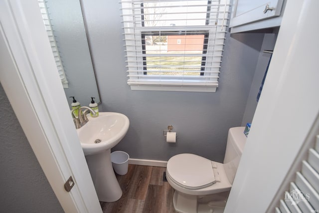 bathroom with a textured wall, toilet, baseboards, and wood finished floors