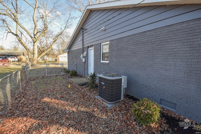 view of side of home featuring central AC unit, crawl space, a fenced backyard, and brick siding