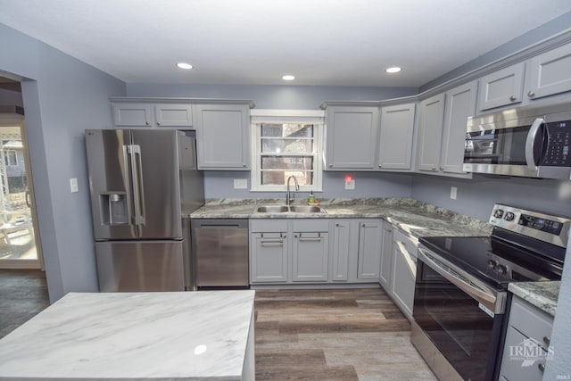 kitchen featuring appliances with stainless steel finishes, dark wood finished floors, gray cabinets, and a sink