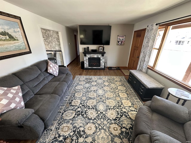 living room featuring dark wood-style flooring and a stone fireplace